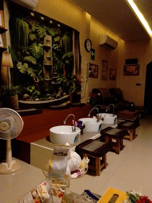 Foot-wash basins and recliners beneath a green jungle wall at Ai Oon Massage Lanna