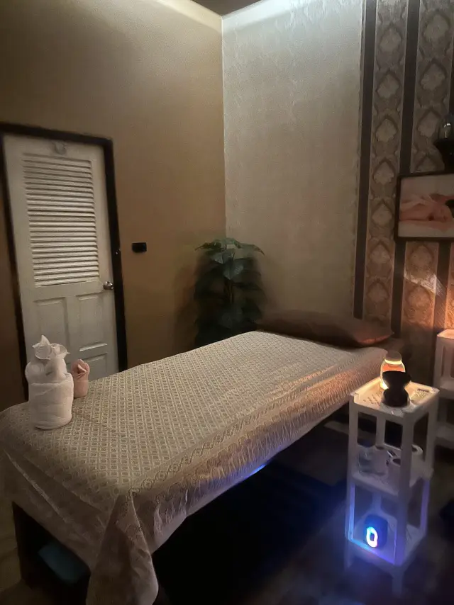Small massage room with a bed, white door and aroma diffuser at Ai Oon Massage Lanna