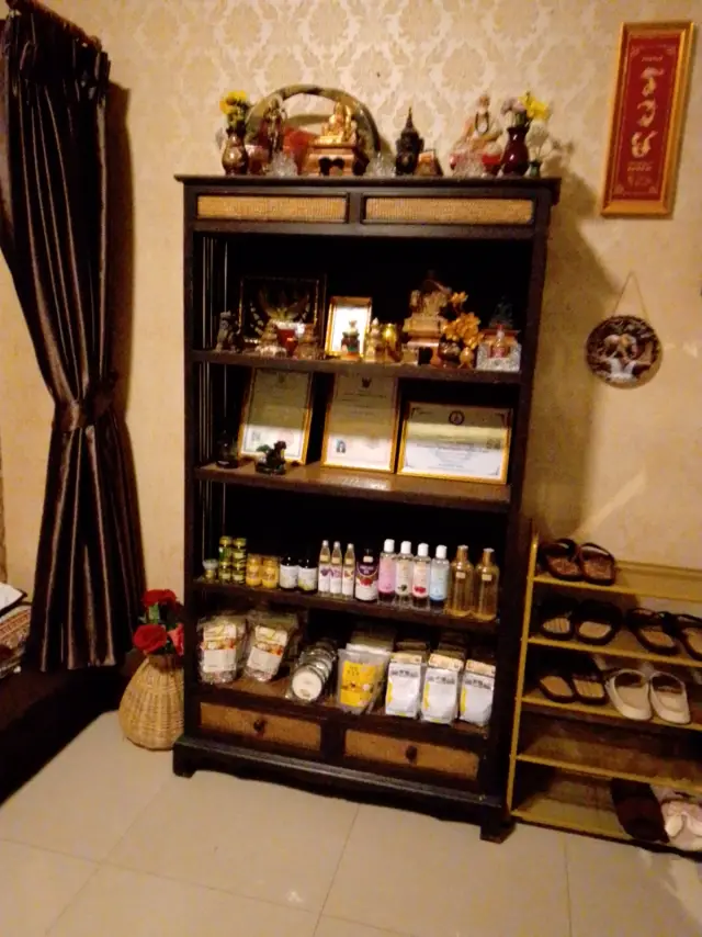 Shelf of Buddha figures, framed certificates and bottled oils at Ai Oon Massage Lanna