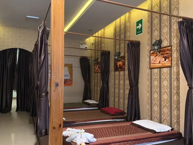 Curtained Thai massage mats with a green exit sign at Ai Oon Massage Lanna in Chiang Mai