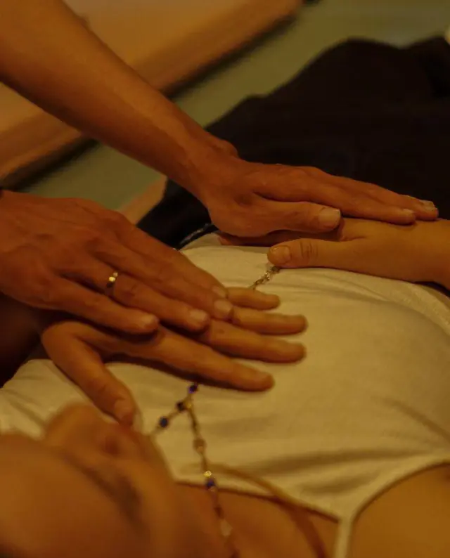 Therapist's hands working on a guest's abdomen over a cloth during a Thai massage