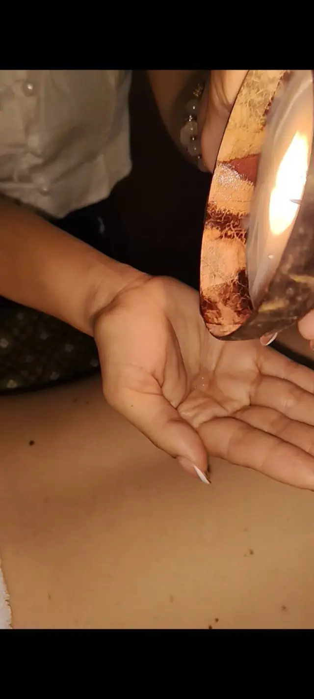 Warm oil from a lit candle poured into a hand during a candle massage, Chiang Mai