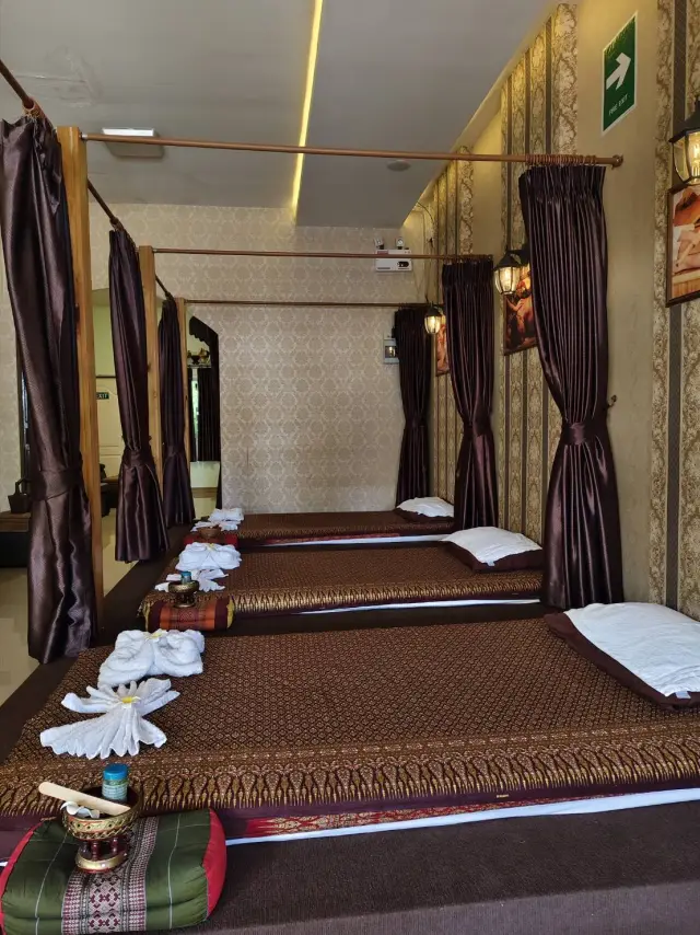 Row of curtained Thai massage mats with white pillows at Ai Oon Massage Lanna