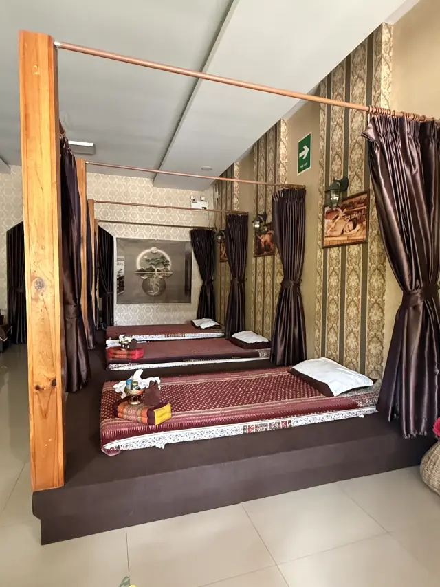 Wide view of curtained Thai massage mats with towels and a pillow at Ai Oon Massage Lanna