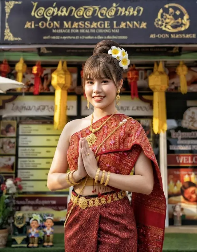 Therapist in traditional Lanna dress greeting with a wai outside Ai Oon Massage Lanna, Chiang Mai