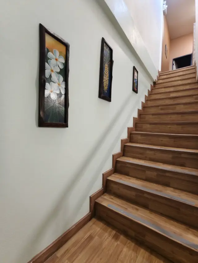 Staircase with framed flower paintings on the wall at the Ai Oon Massage Lanna shop, Chiang Mai