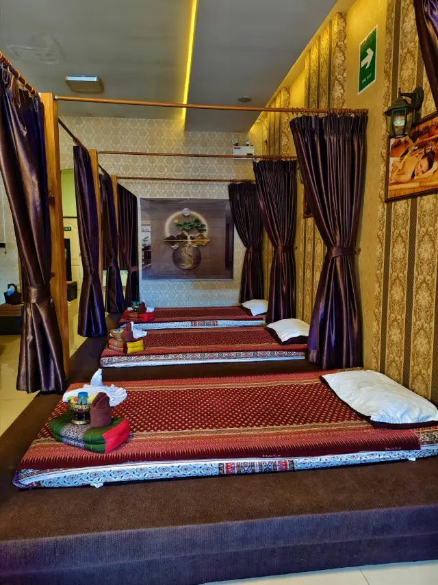 Row of curtained mat beds along a hallway in the Thai massage room at Ai Oon Massage Lanna