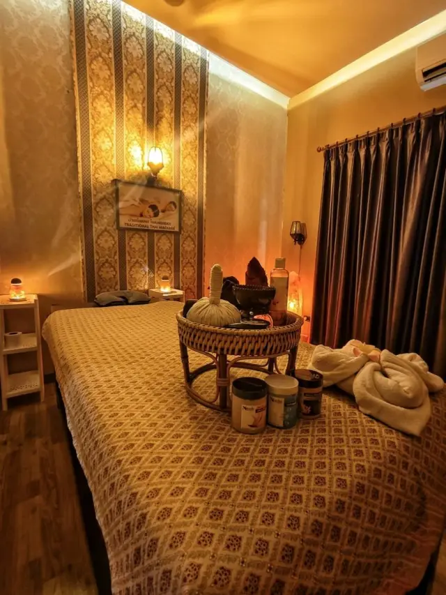 Massage bed with herbal compress balls and oils in a warm-lit treatment room, Chiang Mai