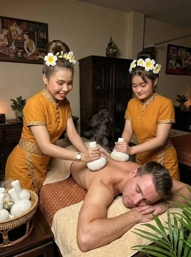 Two therapists applying warm herbal compresses to a guest's back at Ai Oon Massage Lanna