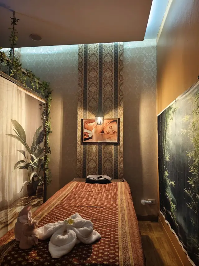 Quiet massage room with a bed, folded towels and a bamboo wall mural in Chiang Mai