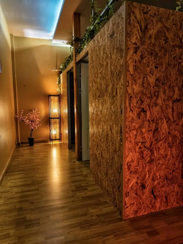 Hallway with a wooden partition, cherry blossom decoration and warm lighting in the massage shop