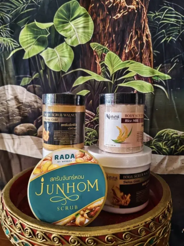 Jars of Junhom body scrub and rice milk scrub in front of a jungle backdrop, Ai Oon Massage Lanna