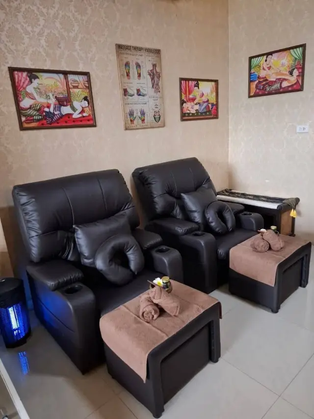 Two black leather massage recliners with footstools and Thai wall art at Ai Oon Massage Lanna
